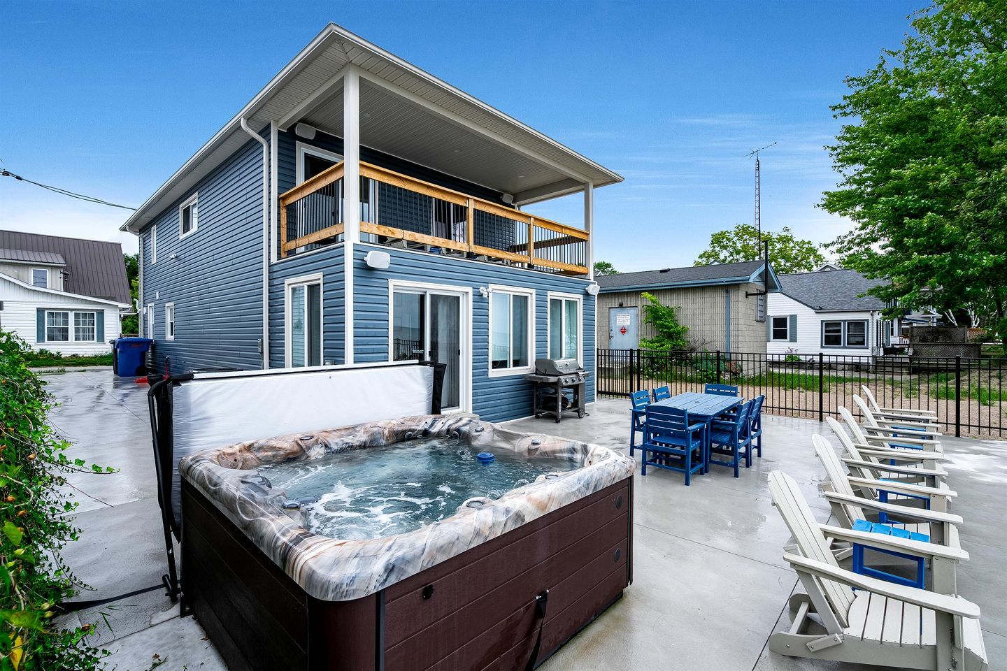 Een tweelaags huis met een jacuzzi, terras en omheinde tuin.