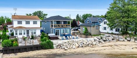 Ein Strandgrundstück mit einem großen Haus, einem kleineren Haus und einem Strandabschnitt mit Felsen und einer Holzterrasse.