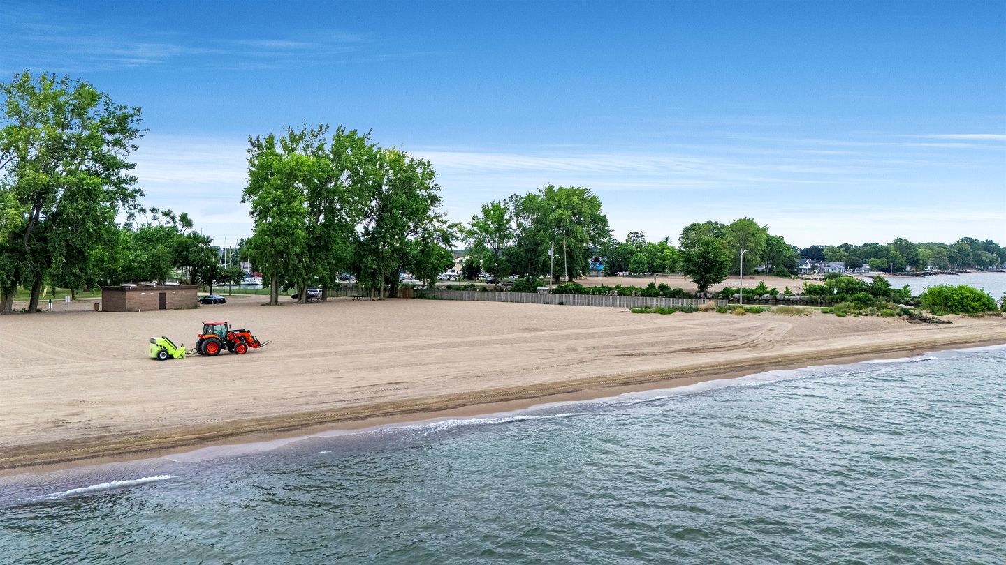 Une plage avec un tracteur et une remorque, des arbres et un ciel dégagé.
