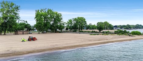 Une plage avec un tracteur et une remorque, des arbres et un ciel dégagé.