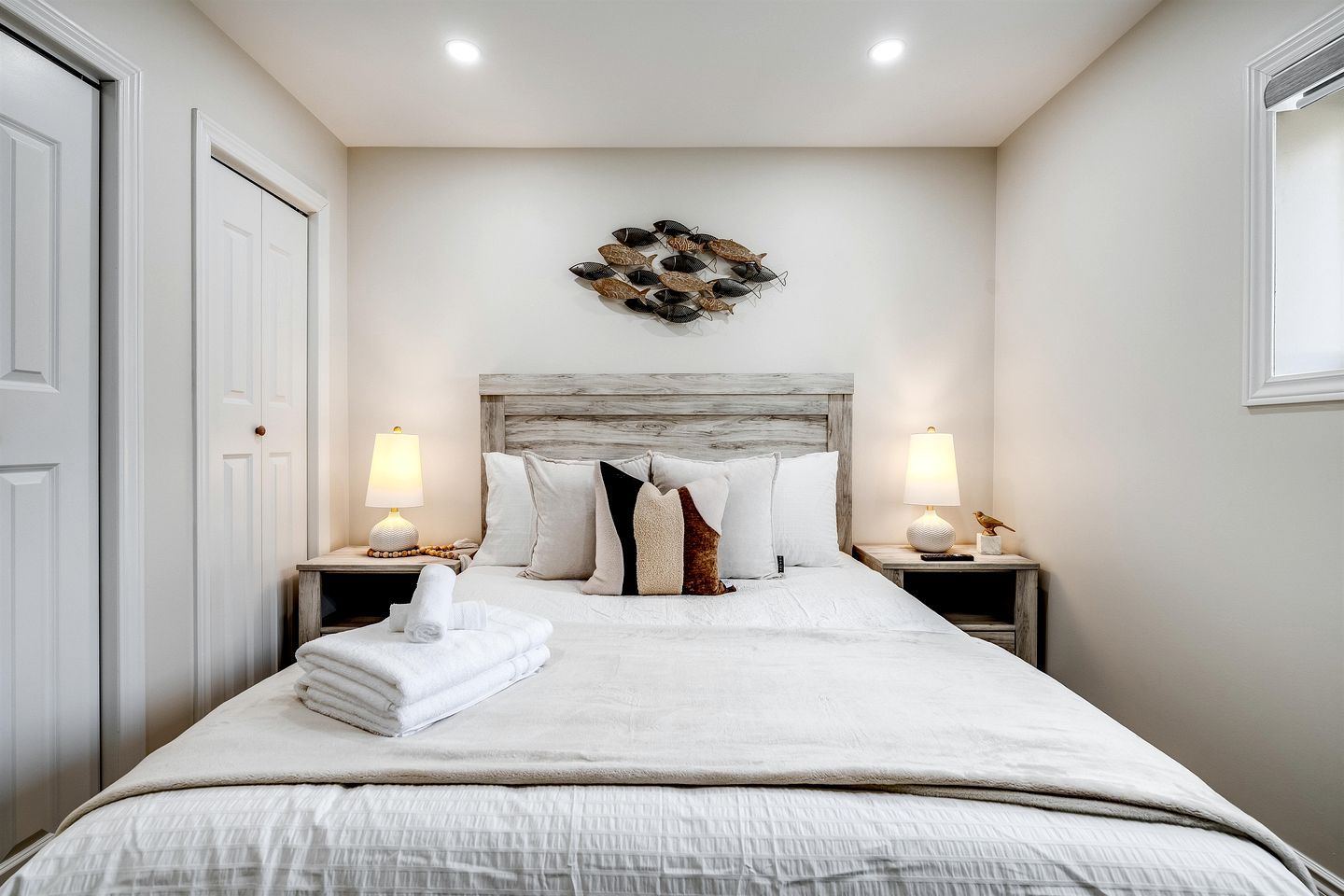 A neatly made bed with a headboard, two bedside tables with lamps, and a wall decoration above the bed.