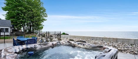 Un jacuzzi con vista al mar, una mesa con sillas y un árbol.