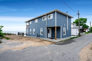 A two-story house with a front porch, a garage, and a visible number '5077' on the side. - Luxurious Beachfront Rental with Hot-Tub and Yard in Canada (Kingsville)