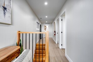 A hallway with a wooden staircase, white walls, and a fire extinguisher on the wall. - Luxurious Beachfront Rental with Hot-Tub and Yard in Canada (Kingsville)