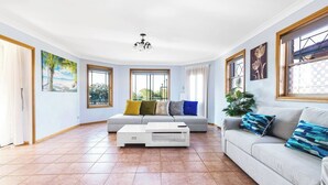 Ein geräumiges Wohnzimmer mit einer Couch, einem Couchtisch und großen Fenstern.