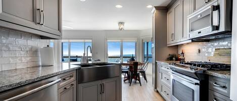 A modern kitchen with stainless steel appliances, a large island, and a view to the outside.