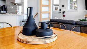 Eine moderne Küche mit weißen Schränken, einem Holztisch und einer schwarzen Vase.