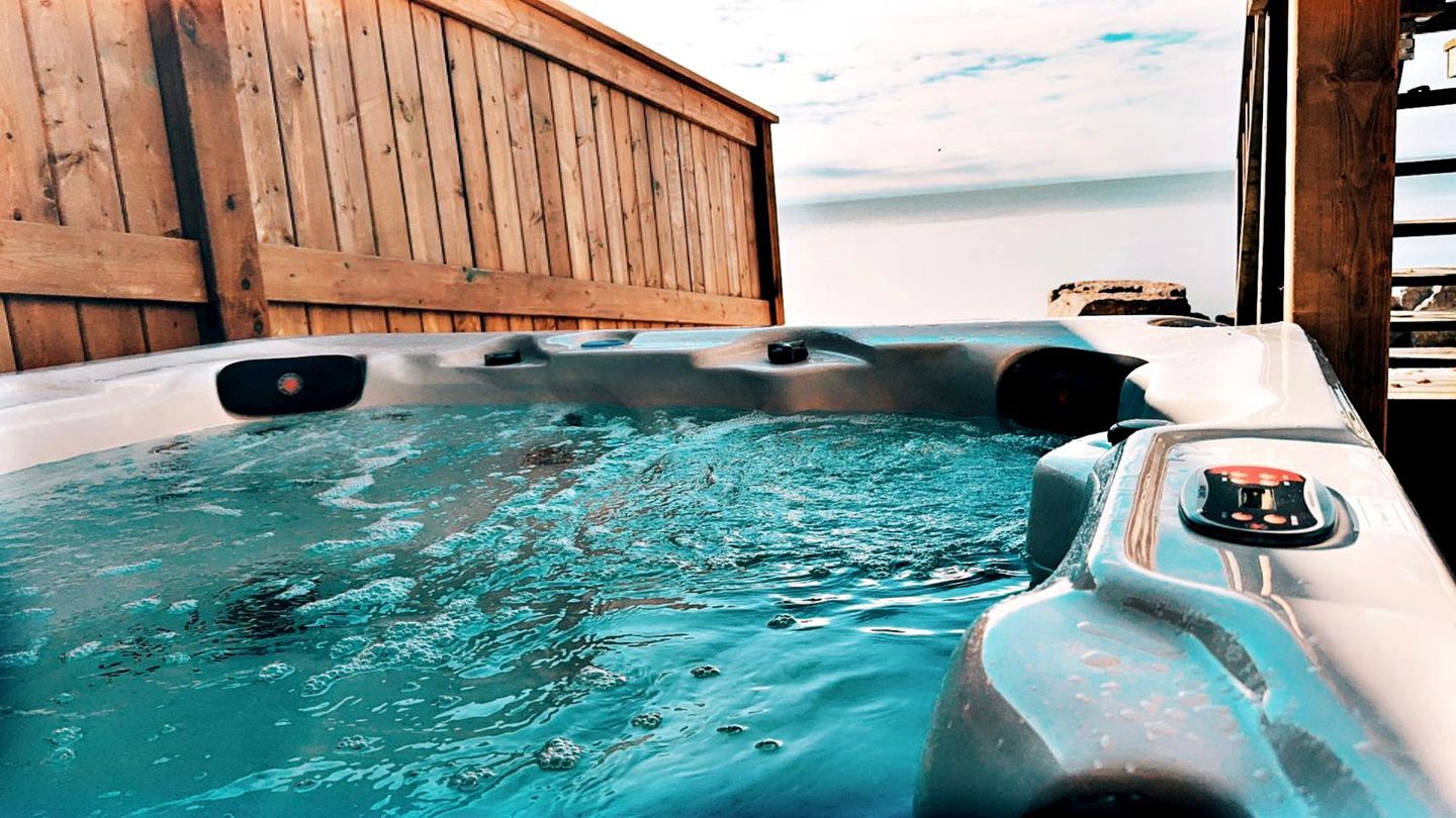 Un jacuzzi con cubierta de madera y vista a la playa.