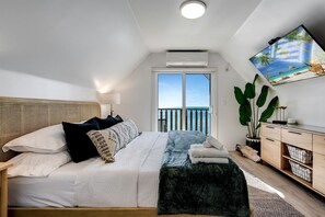 A bedroom with a bed, a TV, a balcony with a view, and a plant. - Beachfront Cottage with Stunning Sights in Leamington, Ontario (Leamington)