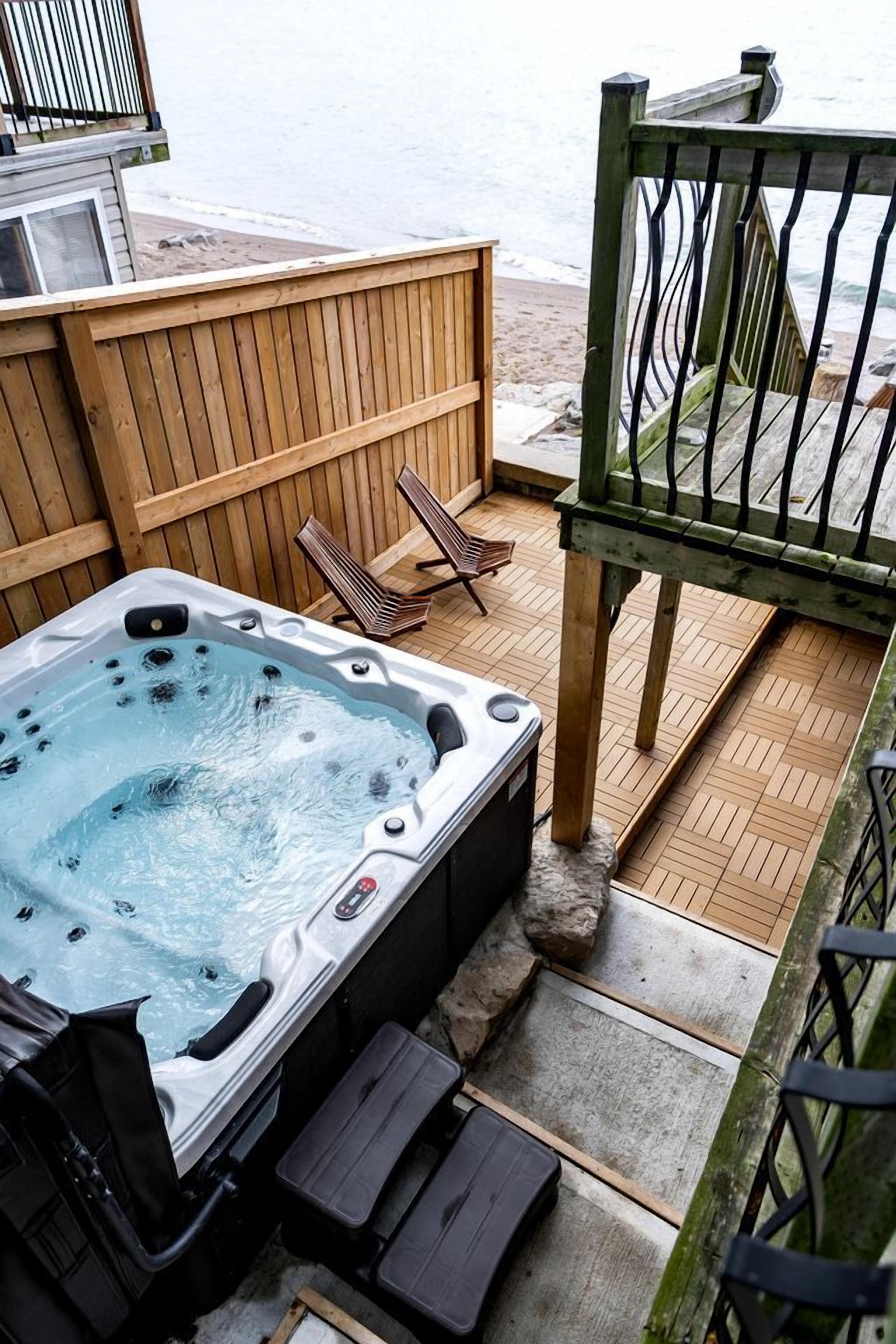 A hot tub on a wooden deck with a view of the beach.