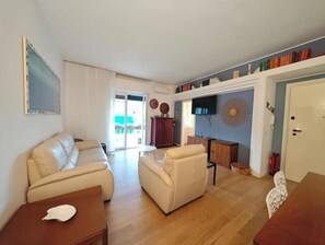 Ein Wohnzimmer mit einer Couch, Sesseln, einem Couchtisch und einem Fernseher.