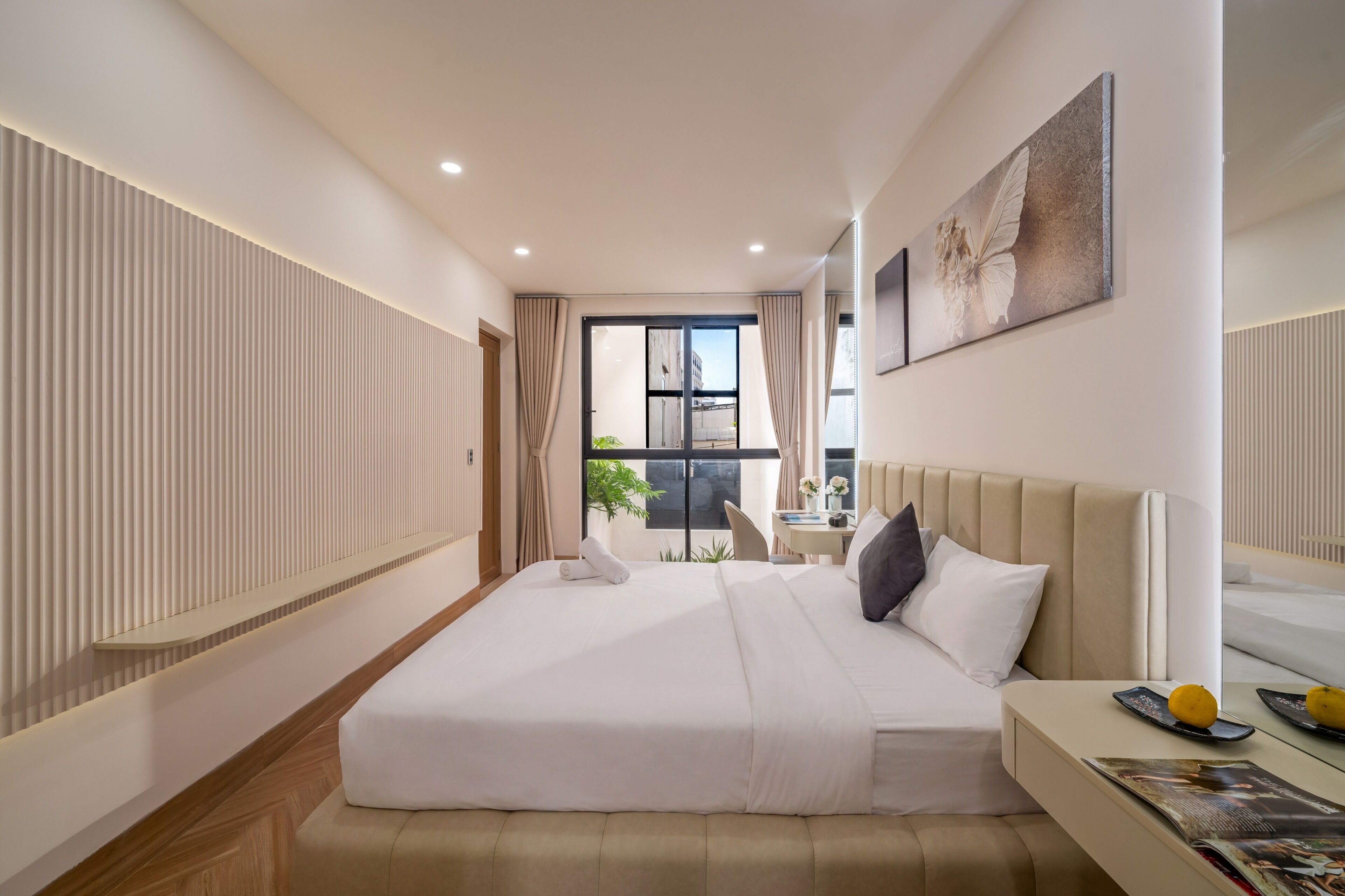 Habitación de hotel moderna con una cama grande, una mesita de noche con una revista, una ventana con cortinas y una obra de arte colgada en la pared.
