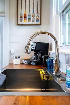 Eine moderne Küche mit Spüle aus Edelstahl, einer Kaffeemaschine und einem Wanddekor.