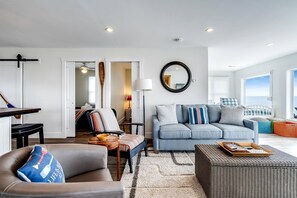 Un salon moderne comprenant un canapé, un fauteuil et un coin repas avec une table et des chaises.