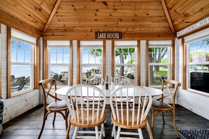 A wooden interior with a 'LAKE HOUSE' sign, a round table, and four chairs. - Impressive Waterfront Cottage with Fantastic Views in Leamington, Ontario (Leamington)