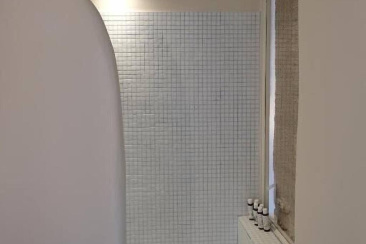 A bathroom with a tiled wall, a window, and a light fixture.