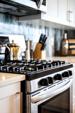 A kitchen with a stainless steel stove, a microwave, and a range hood.