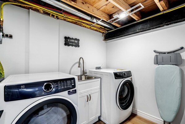 A laundry room with a washing machine, dryer, and ironing board.