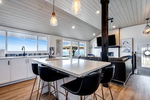 Una cocina moderna con una isla grande, taburetes de bar e iluminación colgante.