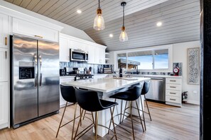 Una cocina moderna con electrodomésticos de acero inoxidable, una isla central con taburetes y vistas al exterior.