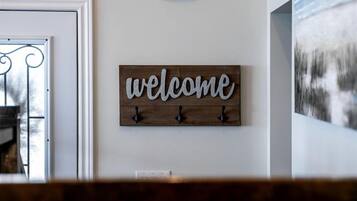 Un escalier avec une rampe en bois, une pancarte indiquant « Bienvenue » et un luminaire fixé au mur.