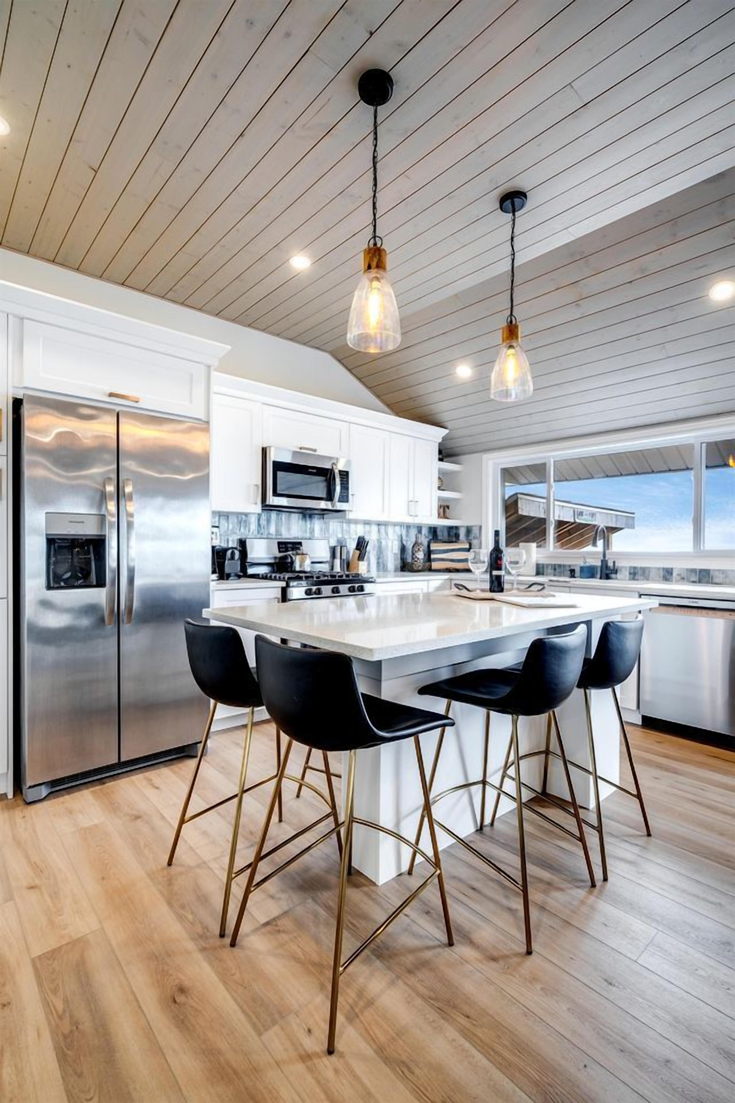 A modern kitchen with a central island, stainless steel appliances, and pendant lighting.
