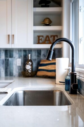 A modern kitchen with a stainless steel sink, a black faucet, and a marble backsplash. - Modern Lake House with Incredible Deck and Jacuzzi in Ontario (Leamington)