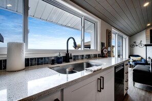 Una cocina moderna con un amplio ventanal, un lavamanos de acero inoxidable y una encimera.
