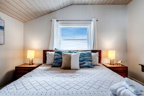 Une chambre à coucher avec un lit, deux lampes de chevet, une fenêtre avec des rideaux et une vue sur le ciel.