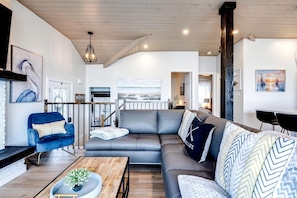 A modern living room with a grey sofa, a blue armchair, and a wooden coffee table.