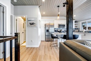 Una cocina moderna con gabinetes blancos, electrodomésticos de acero inoxidable y una barra con taburetes.