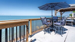 A deck with outdoor furniture and a view of the ocean. - Modern Lake House with Incredible Deck and Jacuzzi in Ontario (Leamington)