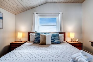 Une chambre à coucher avec un lit, deux lampes de chevet, une fenêtre avec des rideaux et une vue sur le ciel.