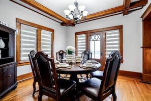 A dining room with a round table, four chairs, a chandelier, and wooden paneled walls. - Stone Farm Retreat with Foosball and Poker Table in Ontario (Kingsville)