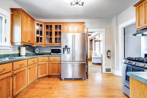 A kitchen with wooden cabinets, stainless steel appliances, and a visible fire extinguisher. - Stone Farm Retreat with Foosball and Poker Table in Ontario (Kingsville)