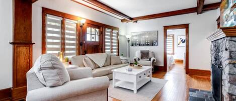 A living room with a fireplace, wooden beams, a sofa, a coffee table, and a painting.