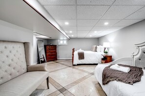 A hotel room with a bed, a sofa, a dresser, and a mirror. - Stone Farm Retreat with Foosball and Poker Table in Ontario (Kingsville)