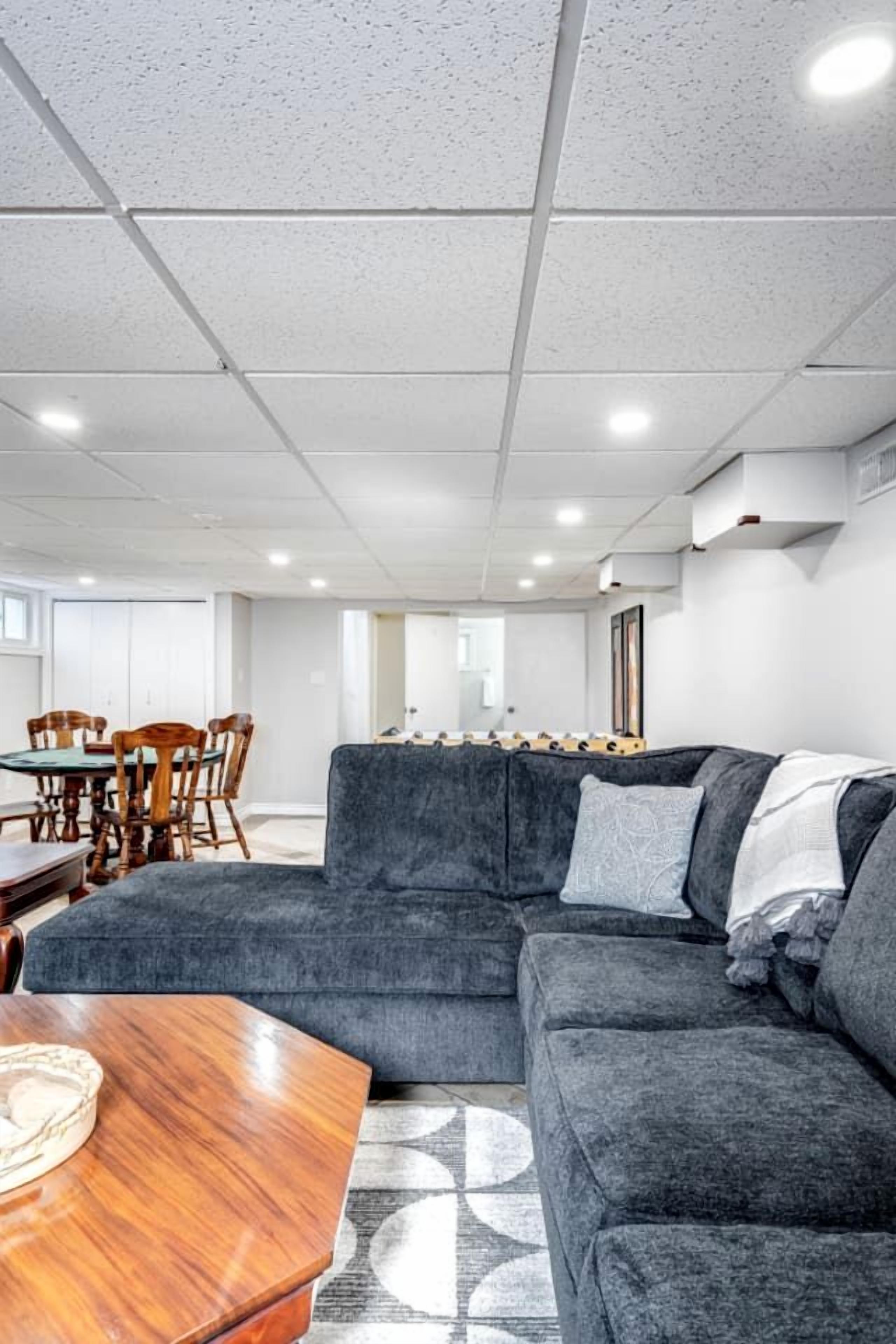 Una sala moderna con un sofá seccional, una mesa de comedor de madera y sillas.