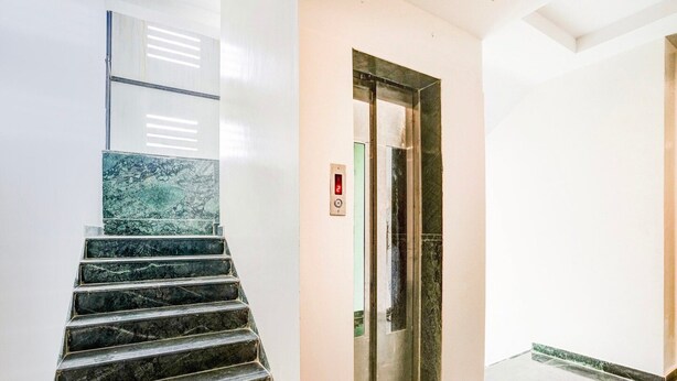 A marble staircase leading to an elevator in a modern building. - Collection O Shirdi Near Sai Baba Temple (Rahata)
