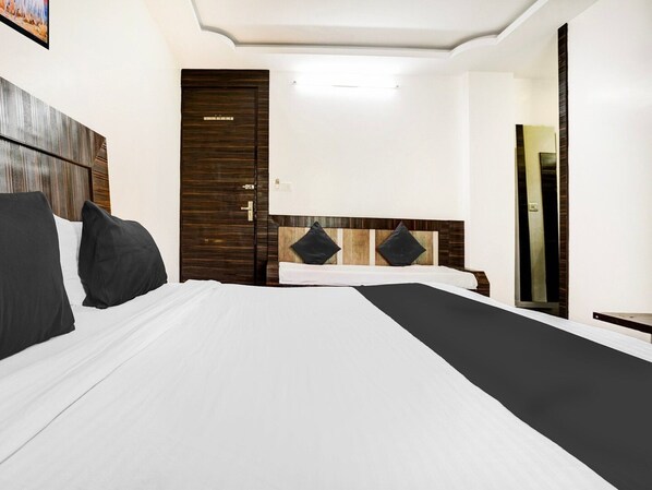A hotel room with a large bed, a wooden wardrobe, a mirror, and a door.