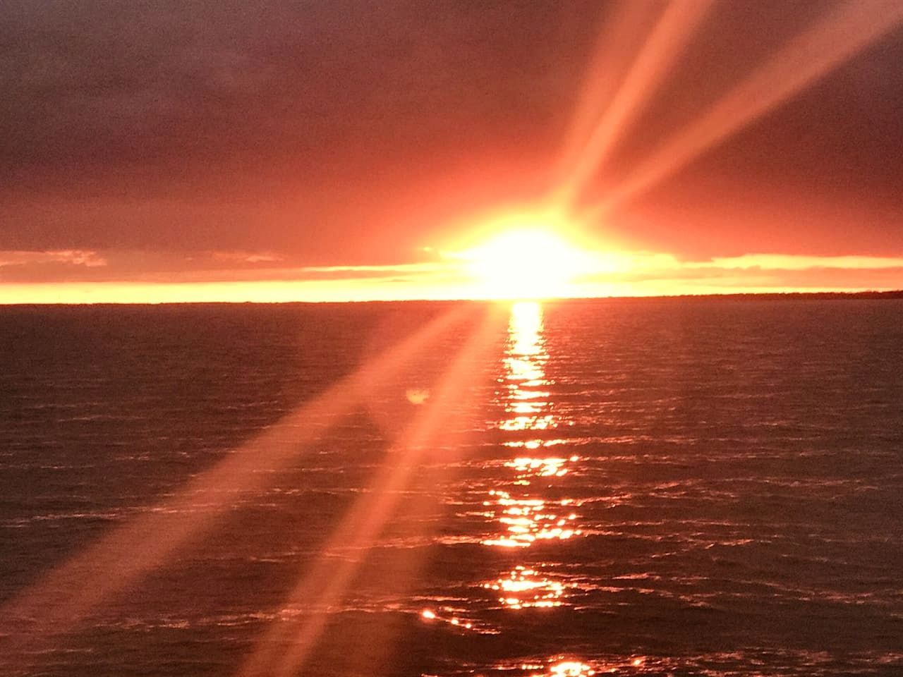A sunset over the ocean with sunlight reflecting on the water.