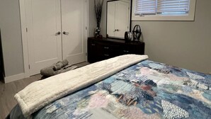 A bedroom with a bed, a dresser, a mirror, a window with blinds, and a door. - Outstanding Cottage with Nice Beach Sights in Leamington, Ontario (Leamington)
