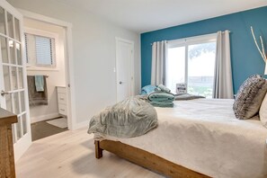 A bedroom with a bed, a window with curtains, a door, and a view of the outdoors. - Outstanding Cottage with Nice Beach Sights in Leamington, Ontario (Leamington)