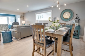 A dining area with a wooden table set for four, surrounded by chairs.