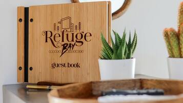 A wooden guest book with 'Refuge Bay Luxury Camping' engraved on it.