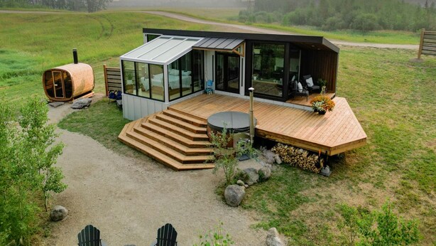 A modern cabin with a glass facade, wooden deck, and a hot tub. - Luxurious Cabin with Outdoor Jacuzzi Great for Couples in Alberta (Cherhill)