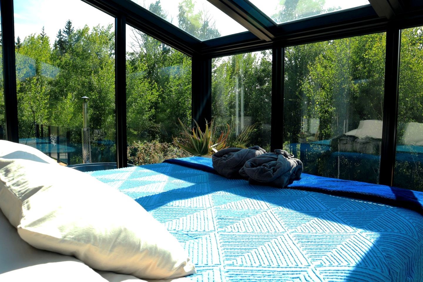 Une chambre avec une grande fenêtre, un lit et un tapis bleu à motifs.