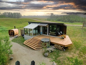 Een moderne chalet met een glazen gevel, een houten terras en een bubbelbad.