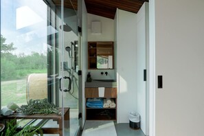 A modern bathroom with a glass door, wooden vanity, and a view of the outdoors. - Luxurious Cabin with Outdoor Jacuzzi Great for Couples in Alberta (Cherhill)