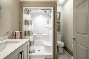 A bathroom with a shower, toilet, and sink.